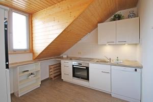 キュールングスボルンにあるApartmentanlage-Ostseeblick-9692の白いキャビネットと木製の天井が備わるキッチン