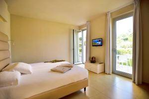 a bedroom with a large white bed and a balcony at Blue Bay Resort in Capo Vaticano +58 photos