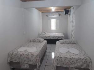 a room with two beds and a tv at Hospedagem do Mineiro in Bonito