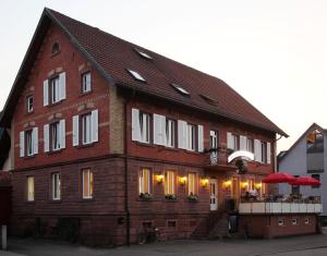 ein großes Backsteingebäude mit weißen Fensterläden in der Unterkunft Restaurant & Appartements In Vino Veritas in Haslach im Kinzigtal