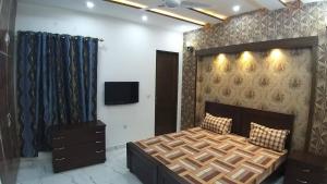 sypialnia z łóżkiem i telewizorem na ścianie w obiekcie Al-Nafay Guest House R1 w mieście Lahaur