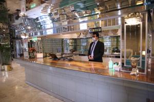 a man in a suit standing behind a counter at Hotel de Papae in Islamabad