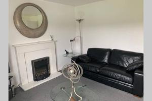 a living room with a black leather couch and a mirror at Spacious Durham City Centre Riverside Apartment in Durham