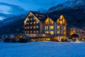 a large building in the snow at night at Hotel Sant'Orso - Mountain Lodge & Spa in Cogne