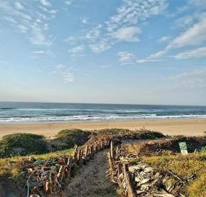 a beach with a wooden fence and the ocean at Cabana Del Mar 69 in Amanzimtoti