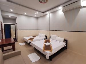 una camera con 2 letti, un tavolo e una scrivania di Invito Guesthouse a Sihanoukville