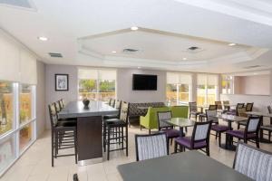 a restaurant with tables and chairs and a flat screen tv at La Quinta by Wyndham Mobile - Daphne in Daphne