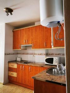 eine Küche mit Holzschränken und einer Mikrowelle in der Unterkunft Rihuete in Puerto de Mazarrón