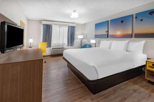 a hotel room with a bed and a flat screen tv at Days Inn by Wyndham Bernalillo in Bernalillo