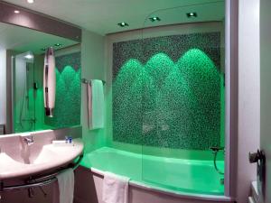 
a bathroom with green walls and a green shower curtain at Ibis Styles Linz in Linz
