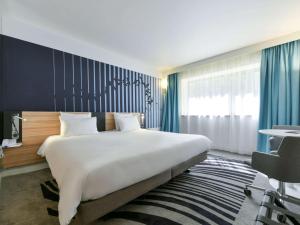 - une chambre avec un grand lit et un mur bleu dans l'établissement Novotel La Rochelle Centre, à La Rochelle