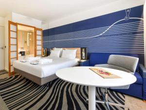 Habitación de hotel con cama, mesa y sofá en Novotel La Rochelle Centre, en La Rochelle