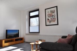 een woonkamer met een bank en een televisie bij Alte Pastorei Minsen in Wangerland