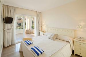 1 dormitorio blanco con 1 cama grande y balcón en Hacienda Playa Elviria Marbella, en Marbella