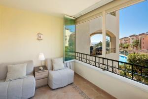 balcón con sofá, silla y ventana en Hacienda Playa Elviria Marbella, en Marbella