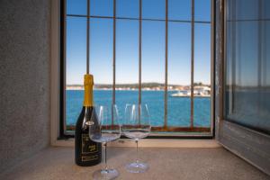 butelkę wina i dwa kieliszki wina przed oknem w obiekcie Apartment Stella Marina Sea view Free Parking w Rovinj +19 zdjęć