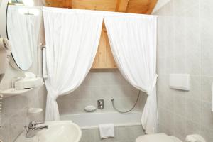 łazienka z umywalką, toaletą i wanną w obiekcie Ciasa Roby w mieście San Cassiano