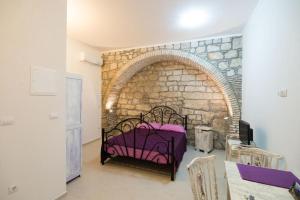 a bedroom with a purple bed in a brick wall at Old Town Budget in Dubrovnik