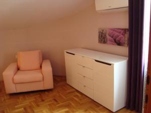 a bedroom with a chair and a dresser at Apartments Eja in Zadar