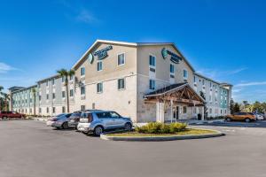 un gran edificio con coches estacionados en un estacionamiento en WoodSpring Suites Bradenton, en Bradenton