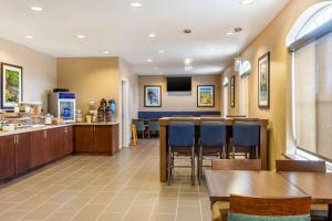 a restaurant with a bar and a kitchen with tables and chairs at Comfort Inn DeKalb - Adjacent the University in DeKalb