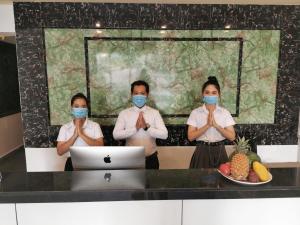 Trzy osoby noszące maski twarzy przed komputerem w obiekcie Invito Guesthouse w mieście Preăh Sihanŭk