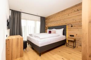 - une chambre avec un lit et un mur en bois dans l'établissement Bichlhof Going, à Going am Wilden Kaiser