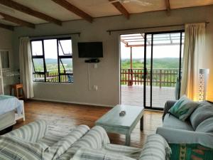 a living room with couches and a television and a balcony at Dune View Cottage in Sodwana Bay