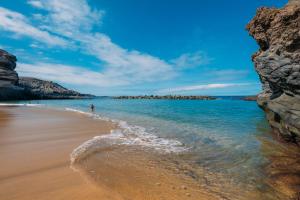 a beach with a person walking in the water at Las Terrazas de Abama Suites in Guía de Isora