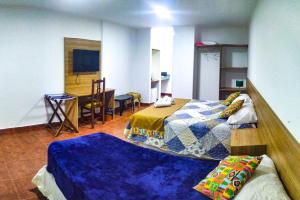 a room with two beds and a table and a room with at Mediterráneo Suites in Puerto Iguazú