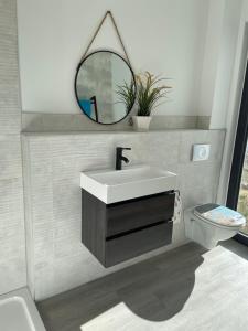 a bathroom with a sink and a toilet and a mirror at Ferienwohnung Strandkieker 2 in Ueckermünde