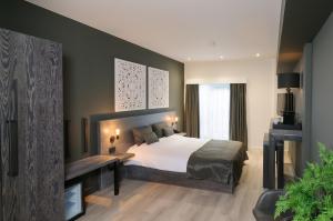 a bedroom with a bed and a desk in it at Hotel De Rustende Jager in Nieuw-Vennep