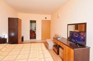 a living room with a bed and a flat screen tv at Guest House California in Pomorie