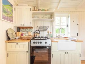 a kitchen with white cabinets and a stove and a sink at Westfield House Farm in Rothbury