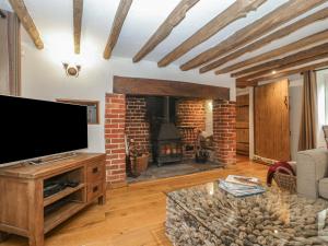 a living room with a television and a brick fireplace at Under Acre Cottage in Blandford Forum