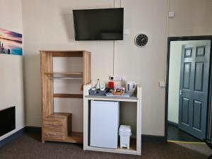 a room with a table with a tv on a wall at Royal Albion Walton in Walton-on-the-Naze