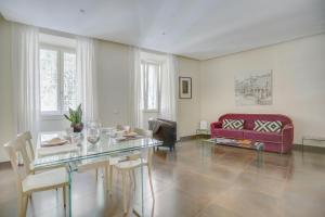 een woonkamer met een glazen tafel en een rode bank bij Colosseo Gardens - My Extra Home in Rome