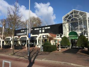 Un gran edificio blanco y negro en una calle. en Hotel De Rustende Jager, en Nieuw-Vennep