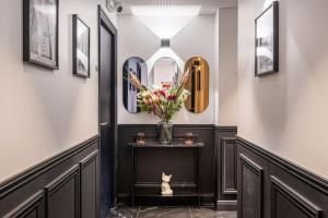 a hallway with a vase of flowers and a cat sitting on a table at Hôtel Mijo's in Fontenay-sous-Bois +30 photos