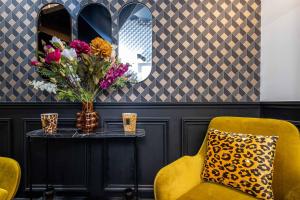 a room with a table with a vase of flowers at Hôtel Mijo's in Fontenay-sous-Bois