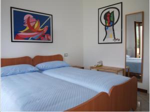 a bedroom with a bed with blue sheets and paintings on the wall at Nora Casa Vacanze in Dervio
