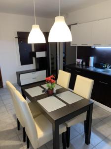 a dining room table with white chairs and two lights at Várlak Apartman in Dinnyés