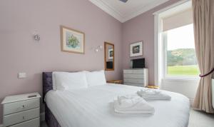 a bedroom with a bed with white sheets and a window at Arthur's Seat View in Edinburgh