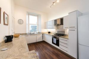a kitchen with white cabinets and a large window at Arthur's Seat View in Edinburgh