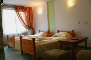 a bedroom with two beds and a table and a window at Family Hotel LILI in Bansko