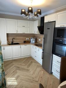 a kitchen with white cabinets and a stainless steel refrigerator at Casa Stef in Sibiu