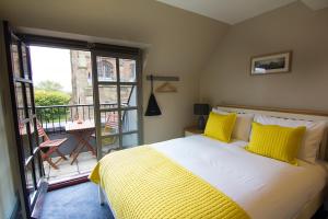 a bedroom with a bed with yellow pillows and a balcony at Church Inn in Ludlow