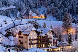 una grande casa nella neve con alberi innevati di Grand Hotel Wolkenstein a Selva di Val Gardena