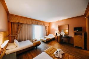 Cette chambre comprend deux lits et une télévision. dans l'établissement SHG Hotel Antonella, à Pomezia