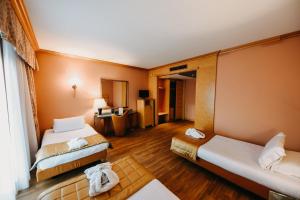 SHG Hotel Antonella في بوميتسيا: غرفه فندقيه سريرين وتلفزيون